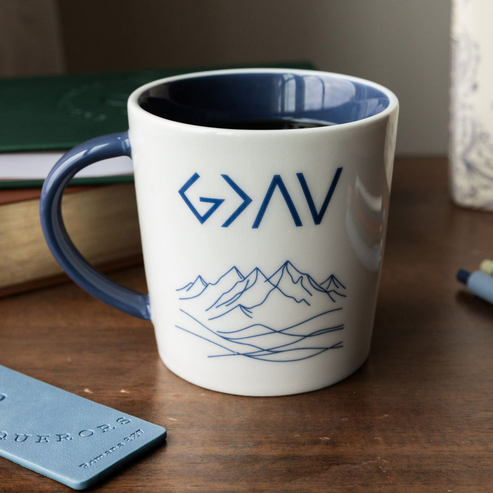 White mug with blue interior and handle, featuring 'G>AV' text and mountain design on a white background.